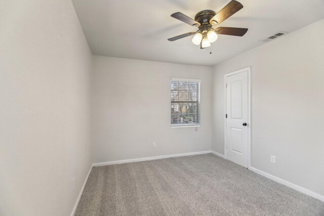 carpeted spare room with visible vents, baseboards, and a ceiling fan