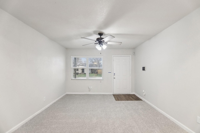 carpeted empty room featuring ceiling fan and baseboards