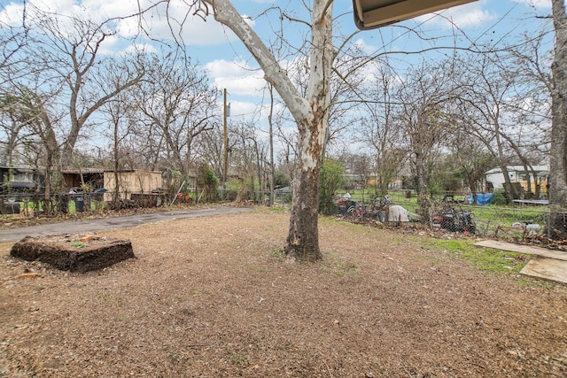 view of yard featuring driveway, a trampoline, and fence