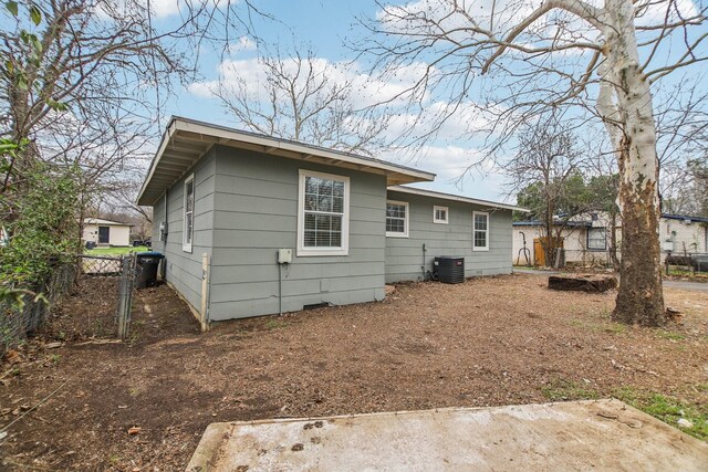 rear view of property featuring central AC unit and fence