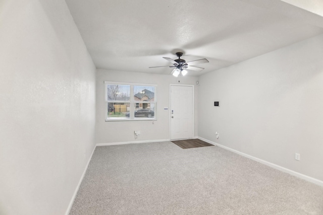 carpeted spare room with a ceiling fan and baseboards