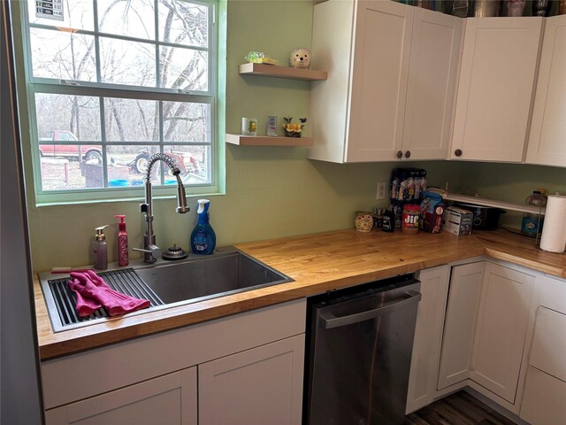 kitchen featuring a sink, stainless steel dishwasher, butcher block countertops, and white cabinets