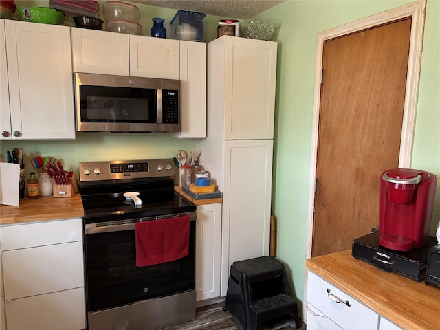 kitchen with butcher block countertops, appliances with stainless steel finishes, and white cabinets