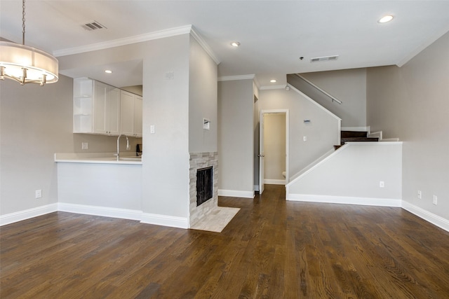 unfurnished living room featuring a sink, visible vents, dark wood finished floors, and stairs