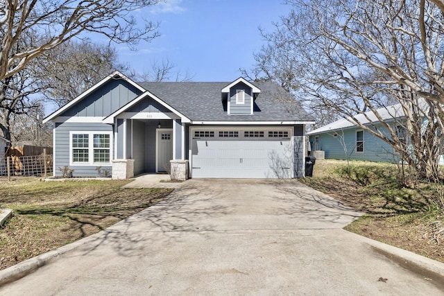 view of front facade featuring an attached garage, board and batten siding, driveway, and roof with shingles