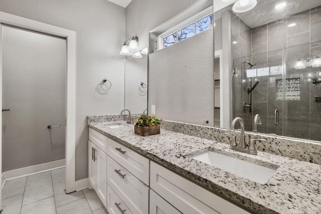 bathroom with double vanity, a shower stall, baseboards, and a sink