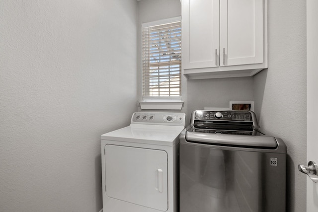 laundry area featuring cabinet space, washer and dryer, and a textured wall