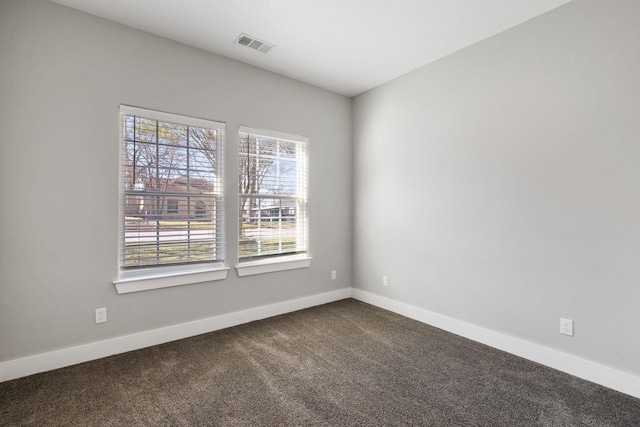 unfurnished room featuring visible vents, baseboards, and dark colored carpet