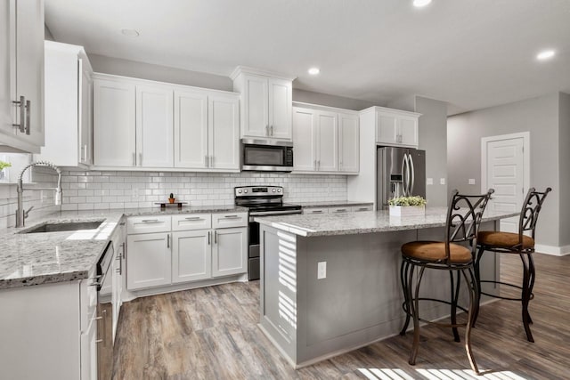 kitchen with a sink, light wood-type flooring, appliances with stainless steel finishes, and white cabinets