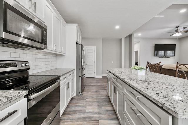 kitchen featuring light stone counters, stainless steel appliances, white cabinets, and dark wood finished floors