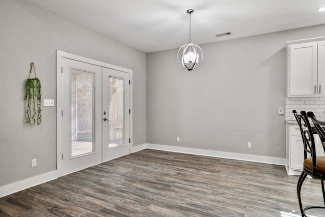 unfurnished dining area featuring dark wood-type flooring, french doors, baseboards, and visible vents