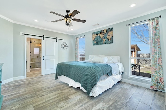 bedroom with a barn door, multiple windows, light wood-style floors, and crown molding