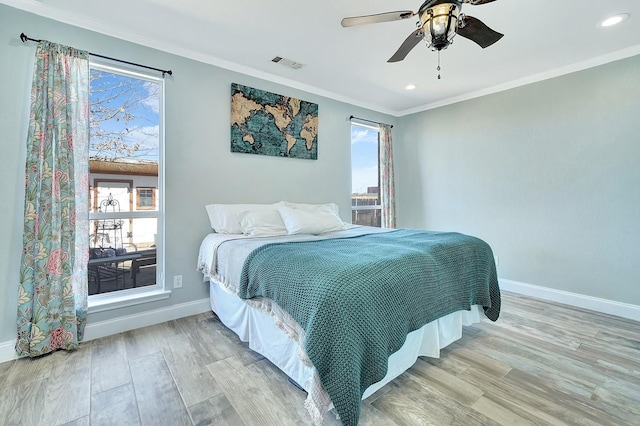 bedroom with visible vents, wood finished floors, baseboards, and ornamental molding