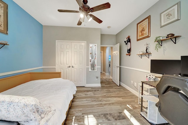 bedroom with a closet, baseboards, light wood-style floors, and a ceiling fan