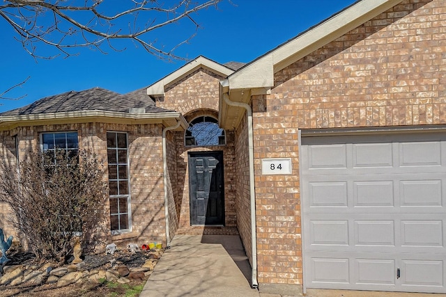 view of front facade featuring brick siding, an attached garage, and a shingled roof