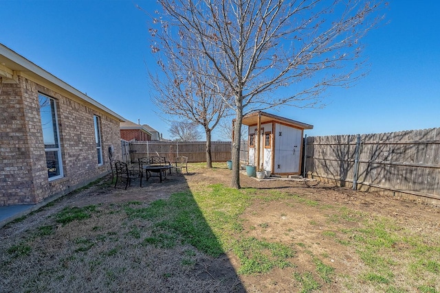 view of yard with an outdoor fire pit, an outdoor structure, a storage shed, and a fenced backyard