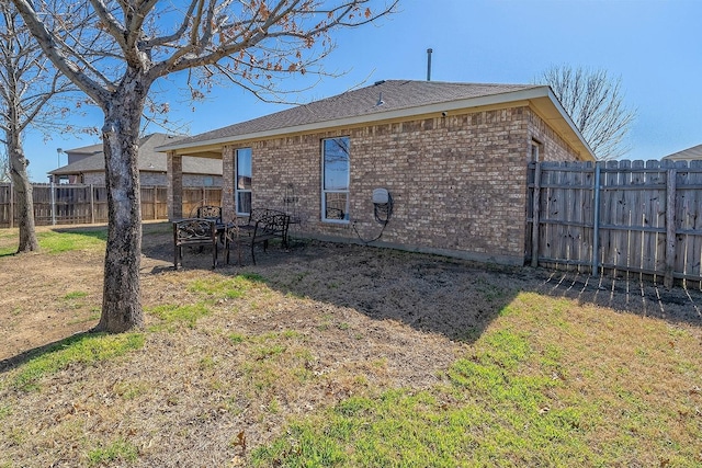 back of property featuring brick siding and fence