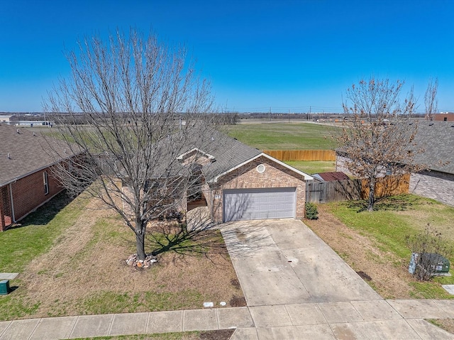 view of front of home with an attached garage, driveway, a front lawn, and fence