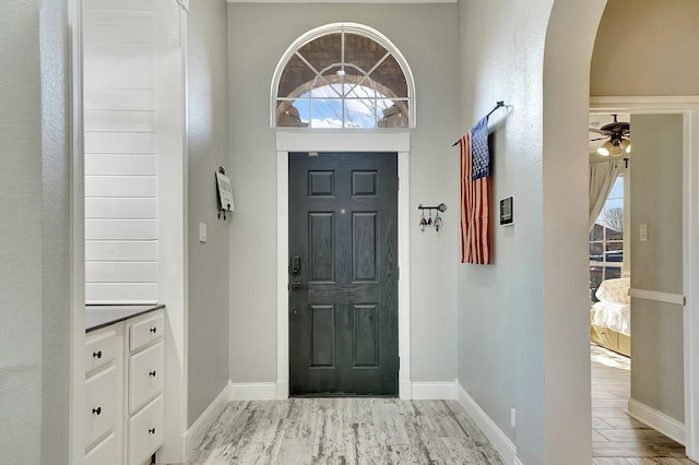 entryway featuring wood finished floors, arched walkways, and baseboards