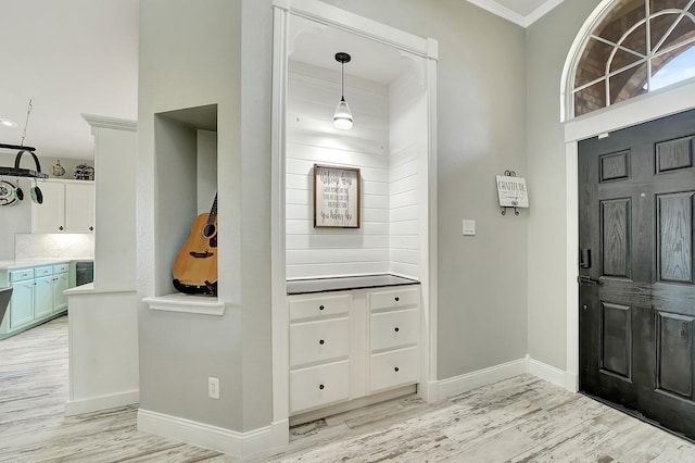 foyer featuring crown molding, light wood-type flooring, and baseboards