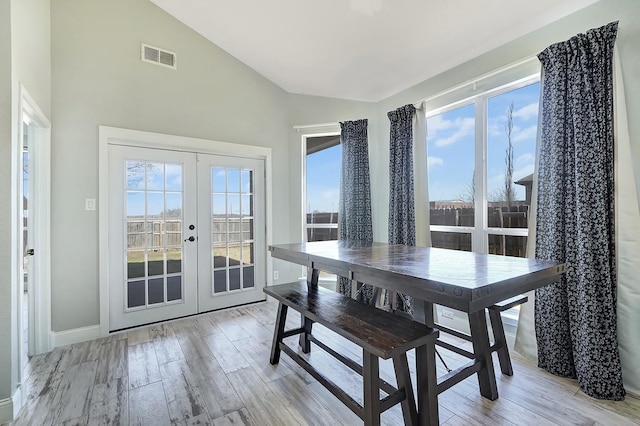 dining area featuring visible vents, baseboards, vaulted ceiling, light wood-style floors, and french doors