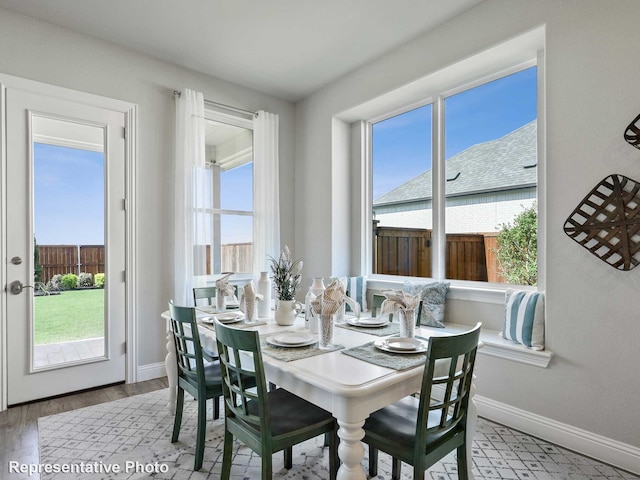 dining space with a wealth of natural light, baseboards, and wood finished floors