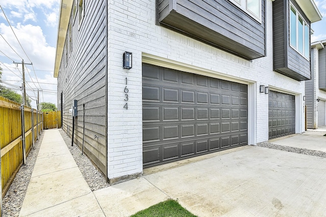 garage featuring concrete driveway and fence