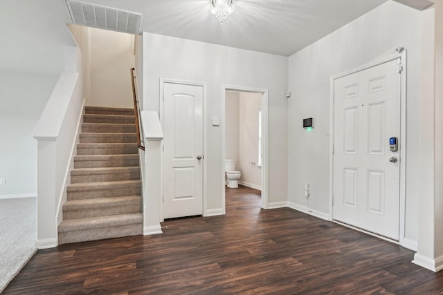 foyer entrance with visible vents, baseboards, dark wood finished floors, and stairway