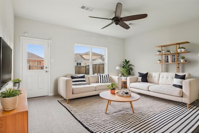 living area with visible vents, a ceiling fan, and carpet