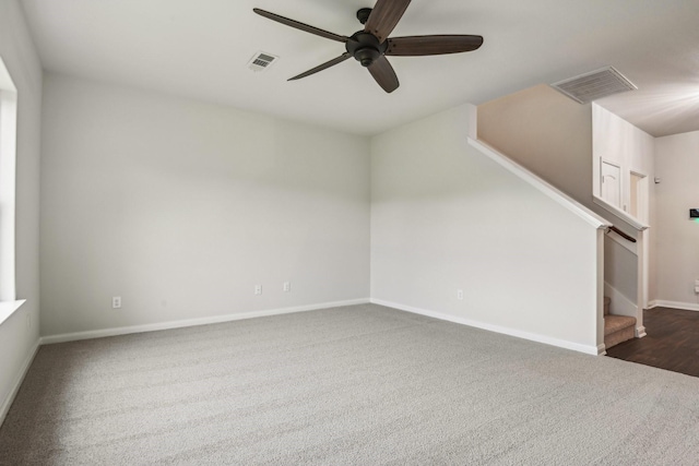 empty room featuring stairs, baseboards, visible vents, and dark carpet