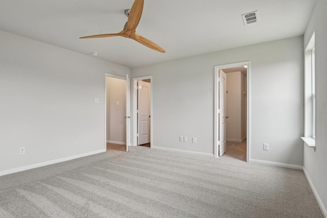 unfurnished bedroom with visible vents, a walk in closet, baseboards, carpet flooring, and a ceiling fan