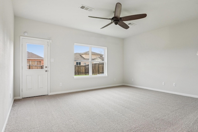 carpeted spare room with visible vents, a ceiling fan, and baseboards