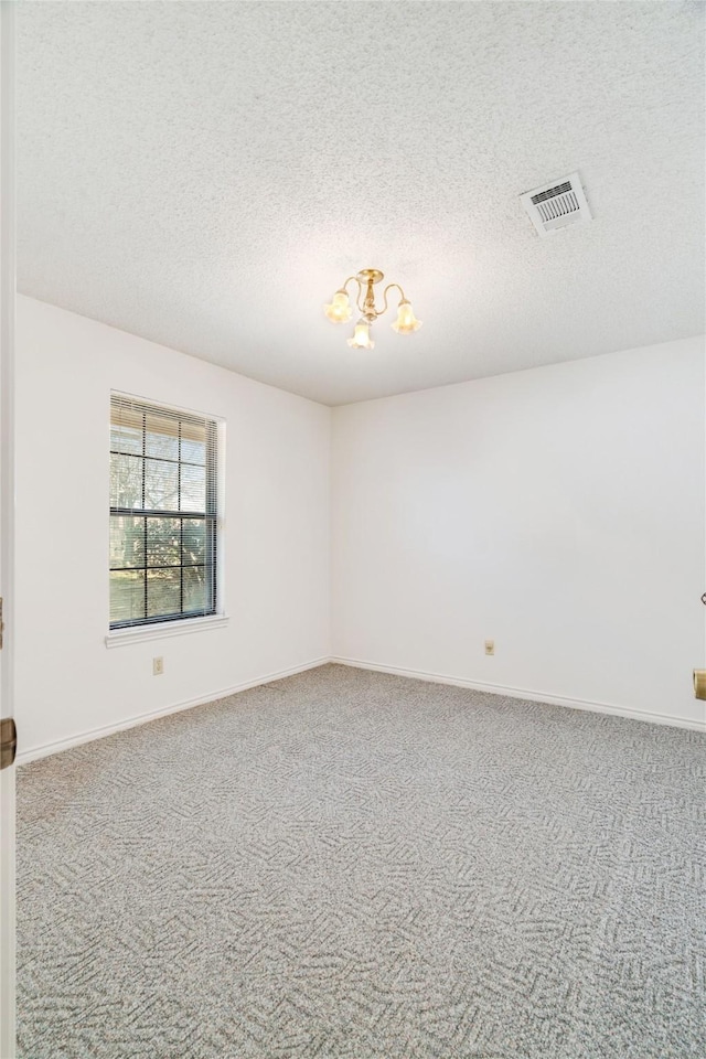 unfurnished room with visible vents, carpet flooring, a textured ceiling, and baseboards