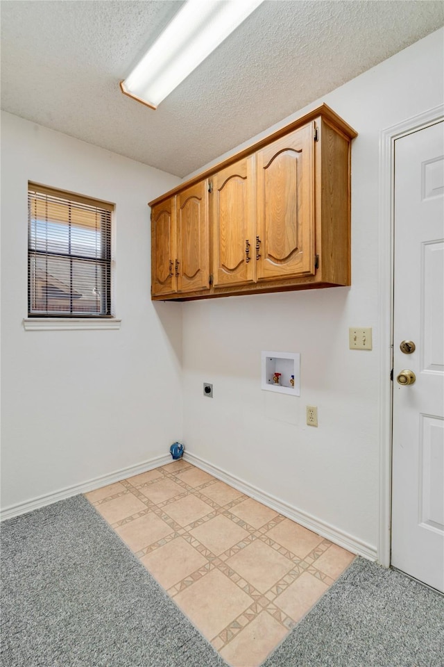 washroom featuring electric dryer hookup, washer hookup, a textured ceiling, cabinet space, and baseboards