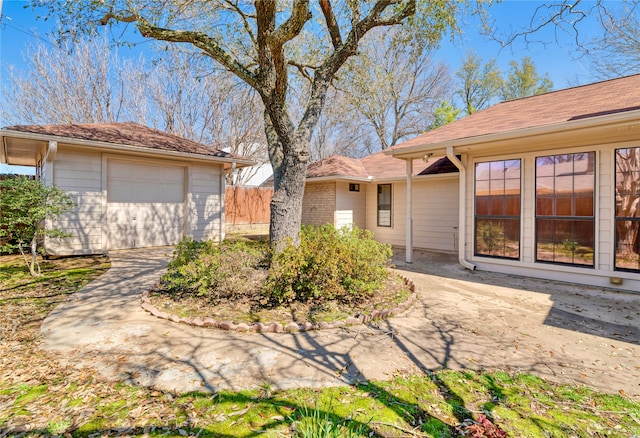 view of front of house with concrete driveway, a detached garage, an outdoor structure, and fence