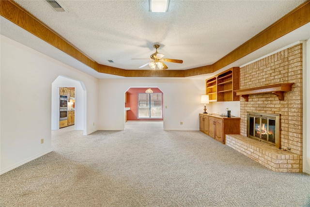 unfurnished living room featuring visible vents, arched walkways, light colored carpet, and a brick fireplace