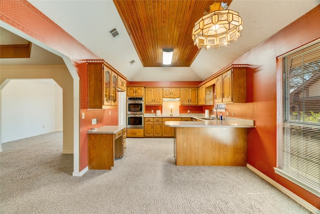 kitchen featuring visible vents, arched walkways, a sink, light countertops, and brown cabinets