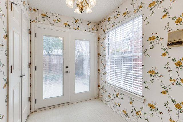 doorway to outside with wallpapered walls, french doors, and a healthy amount of sunlight