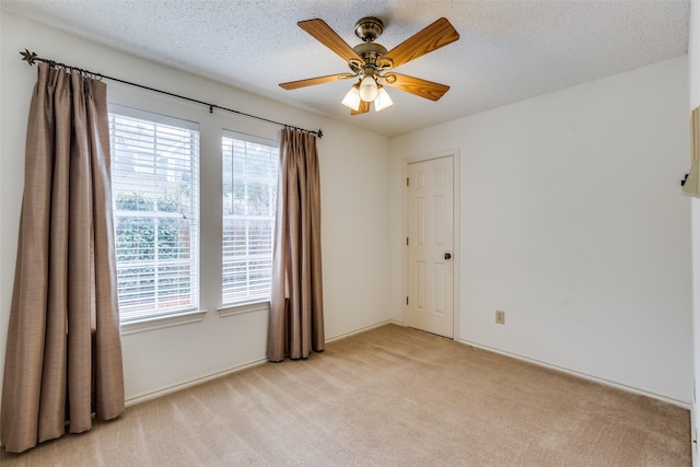 empty room with light colored carpet, a healthy amount of sunlight, ceiling fan, and a textured ceiling