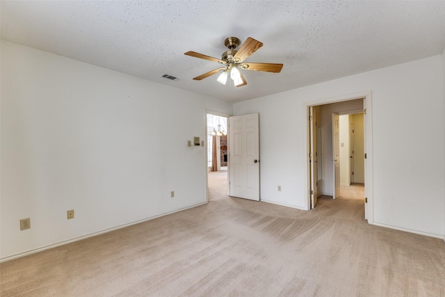 unfurnished bedroom featuring visible vents, light colored carpet, a textured ceiling, and a ceiling fan