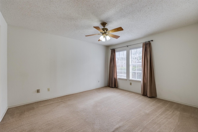 spare room with light colored carpet, a ceiling fan, and a textured ceiling