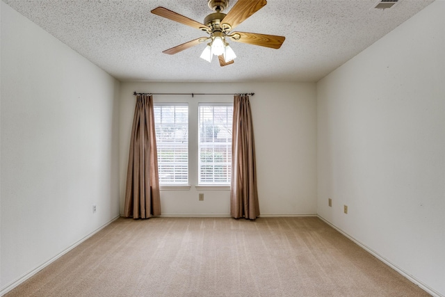 spare room featuring light colored carpet, a textured ceiling, and ceiling fan