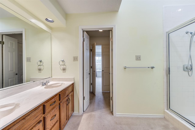 bathroom featuring a sink, baseboards, double vanity, and a tile shower