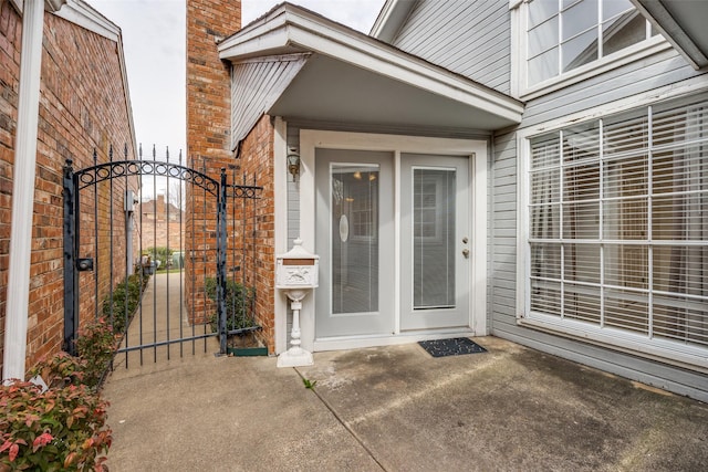 doorway to property featuring brick siding and a gate