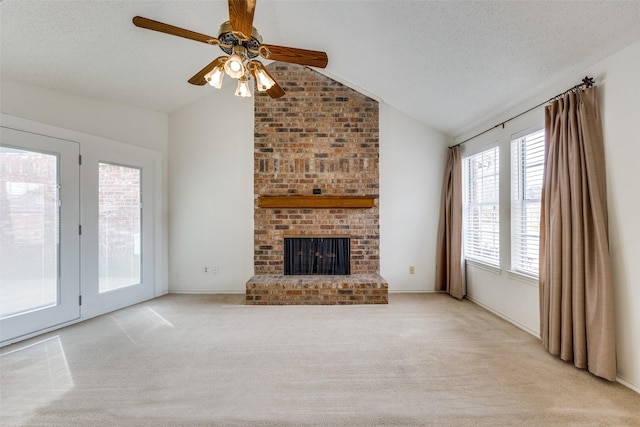 unfurnished living room featuring a ceiling fan, carpet floors, lofted ceiling, a fireplace, and a textured ceiling