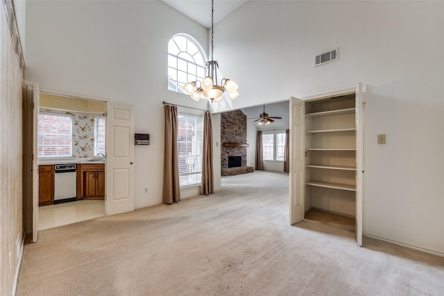 unfurnished living room featuring light carpet, visible vents, a brick fireplace, and high vaulted ceiling