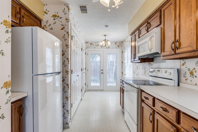 kitchen with wallpapered walls, light countertops, brown cabinets, white appliances, and a textured ceiling