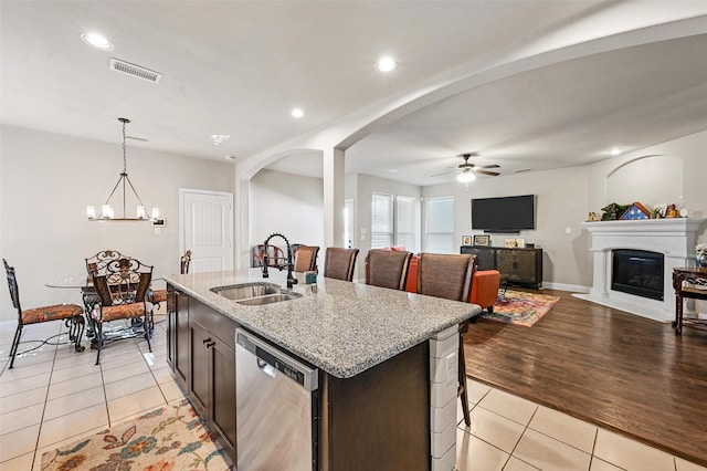 kitchen with visible vents, dishwasher, light tile patterned flooring, a glass covered fireplace, and a sink