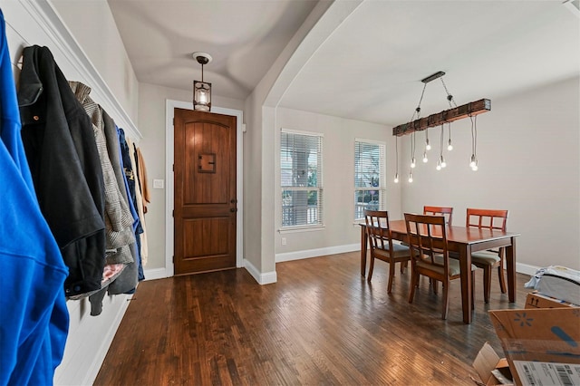 foyer featuring baseboards, arched walkways, and wood finished floors