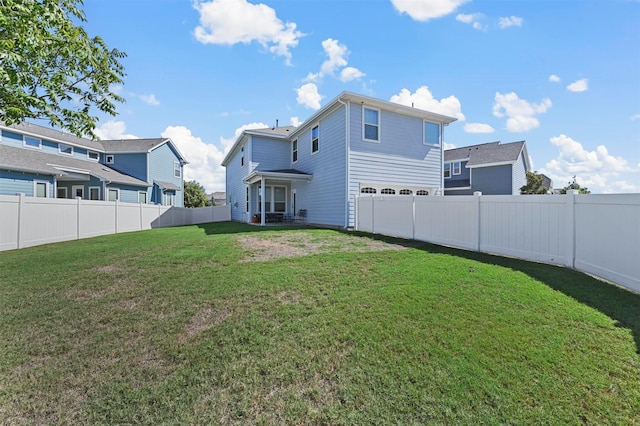 rear view of house featuring a garage, a lawn, and a fenced backyard